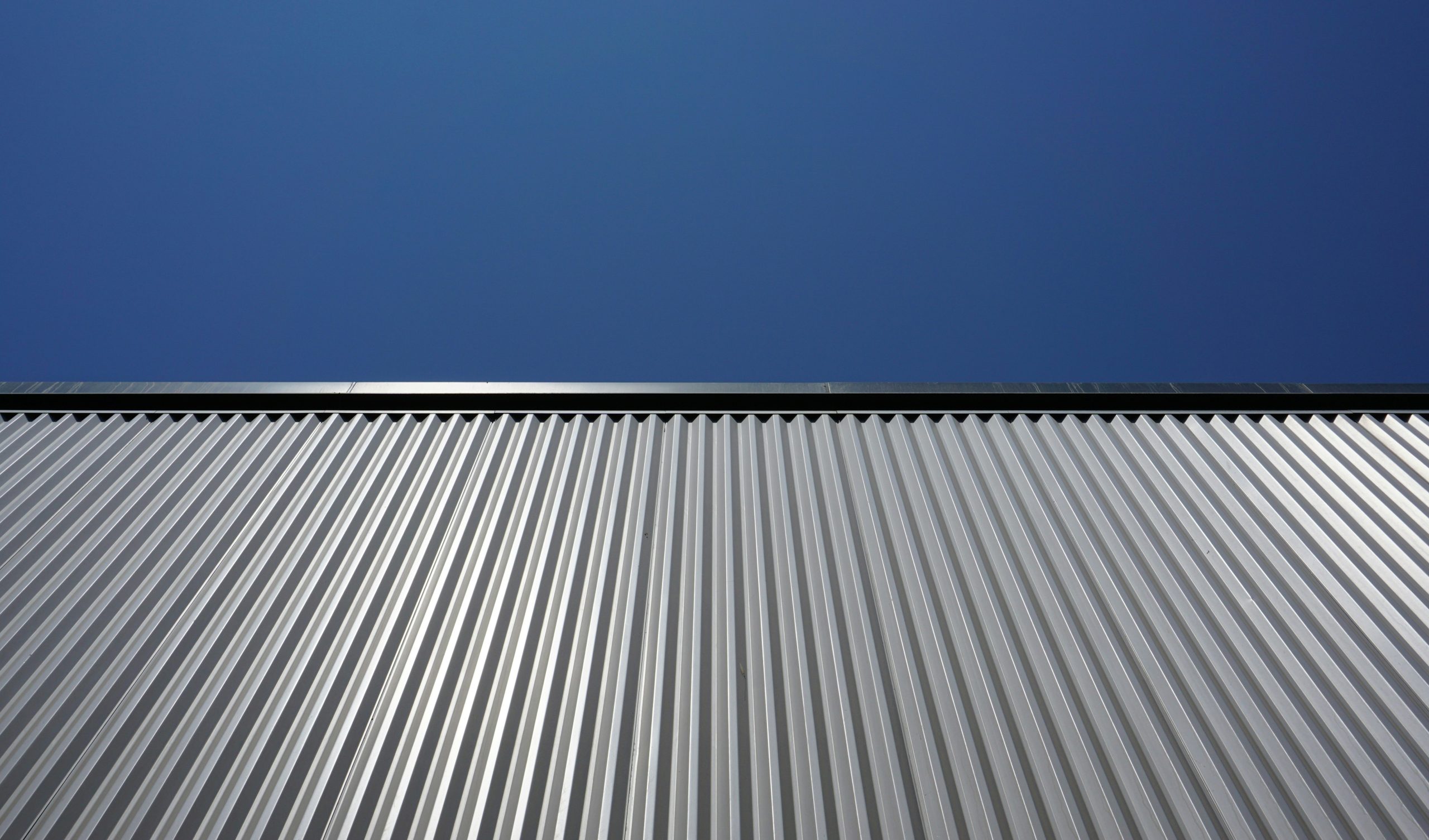 Silver corrugated metal roofing panels against a blue sky