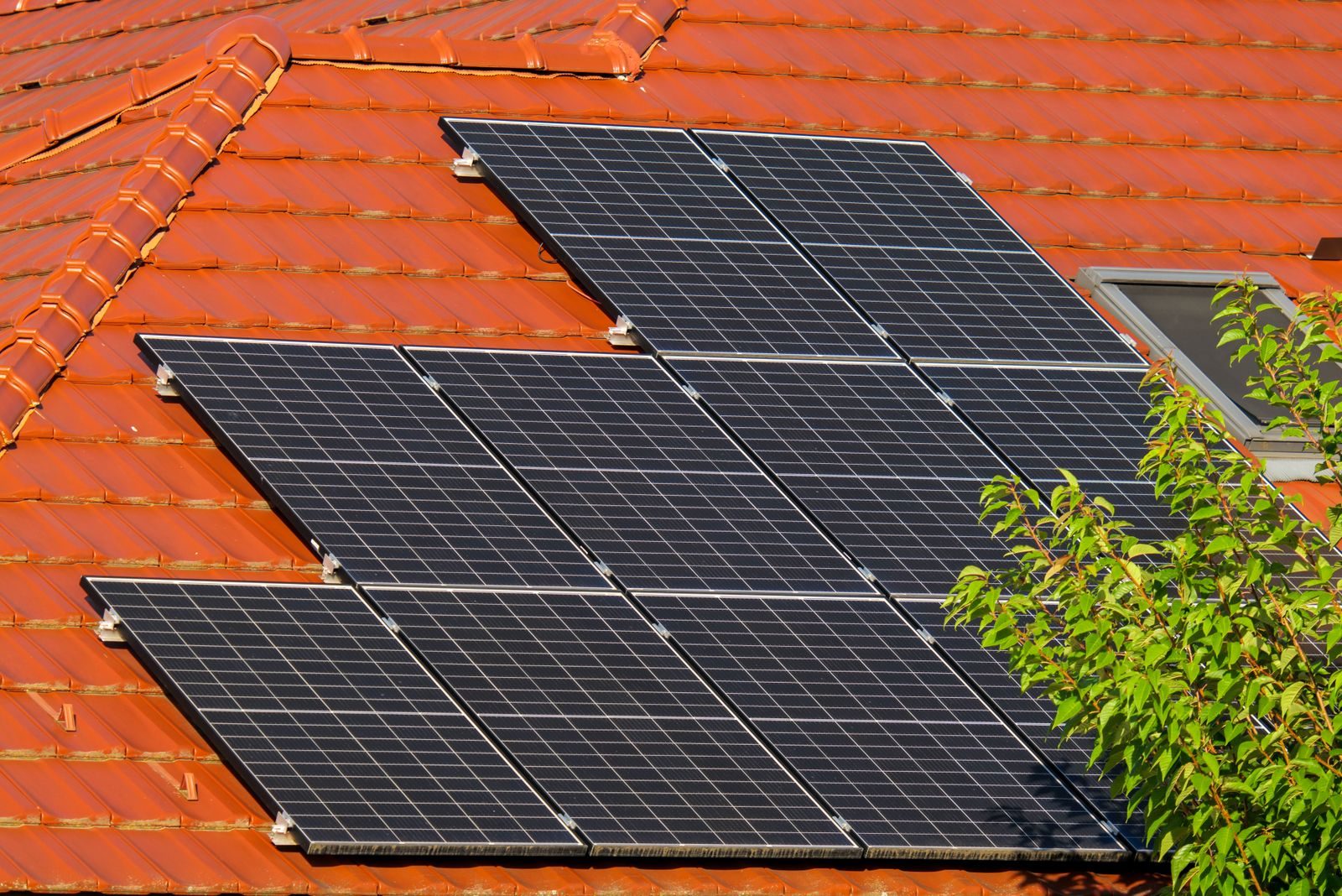 Rows of black solar panels mounted on a red clay tile roof